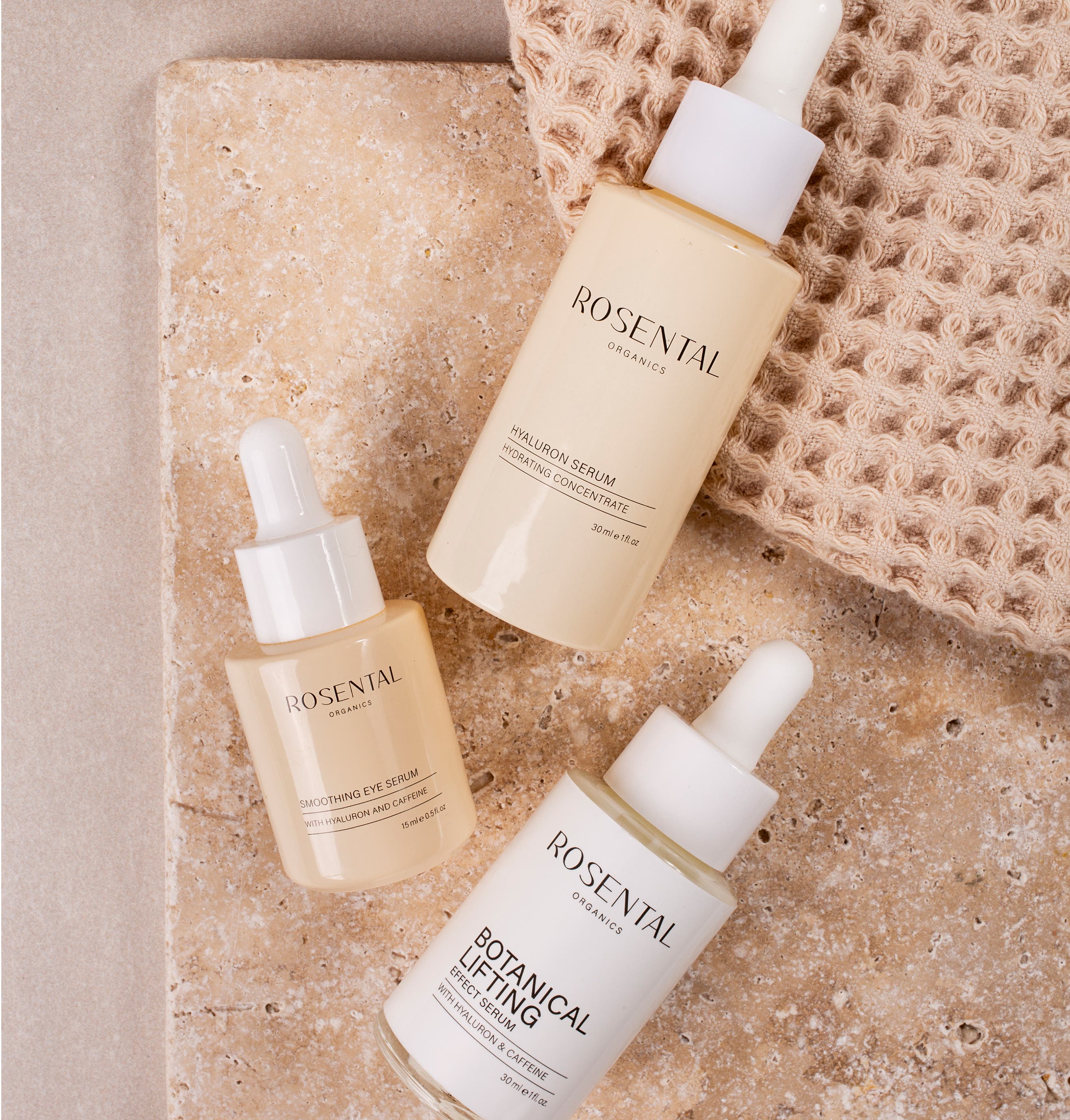 Botanical Lifting Day Routine Produkte von Rosental Organics liegen auf beigefarbenen Marmorstein.